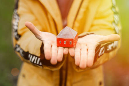 A toy house in the hands of a child. The concept of buying, renting, mortgage housing.の写真素材