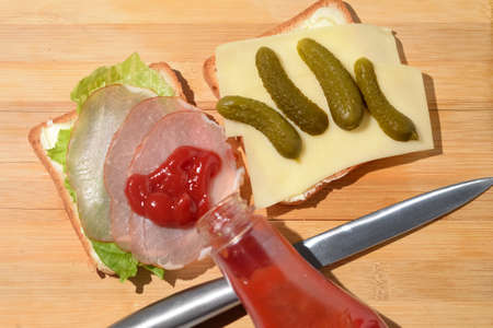 Toast with ham and a leaf of green lettuce poured with ketchup on a wooden background.の写真素材