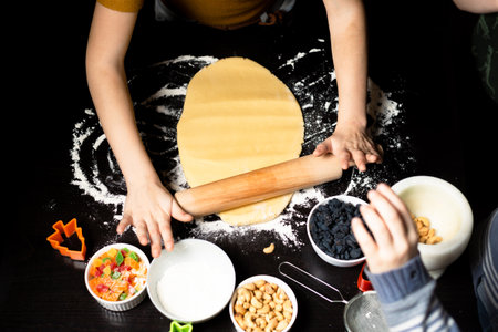 Children cook cookies together. The shortcrust pastry is rolled out with a rolling pin.