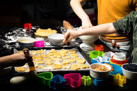 Making cookies by children. Cookies of different shapes are laid out on a baking tray. Joint family...