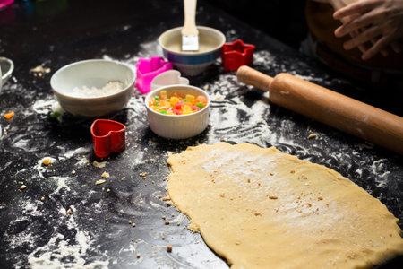 Preparation for making cookies. Rolled out dough and ingredients on the kitchen table.