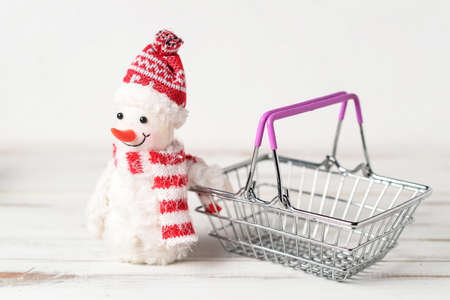Toy snowman and shopping basket on a white background. Winter sales concept.の写真素材