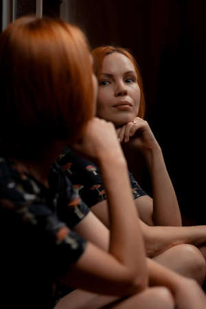 An attractive woman in her forties looks at herself in the mirror. Midlife crisis, depression...