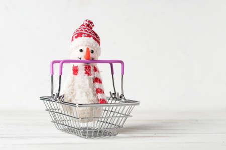 Toy snowman and shopping basket on a white background. Christmas, New Years sales concept.の写真素材
