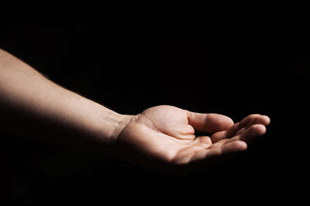 Male hand, palm up on a black background. Giving, asking concept.の写真素材