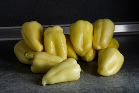 Fresh yellow peppers heap on the kitchen table. Preparation for cooking.