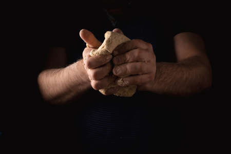 Male hands are making dough on a dark background.の写真素材
