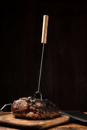 A whole baked piece of meat. A piece of pork in spices cooked in the oven on a wooden board.