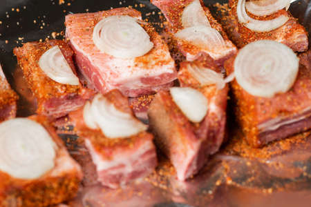 Raw pork ribs with raw onions lie on foil, ready to be baked in the oven.の写真素材