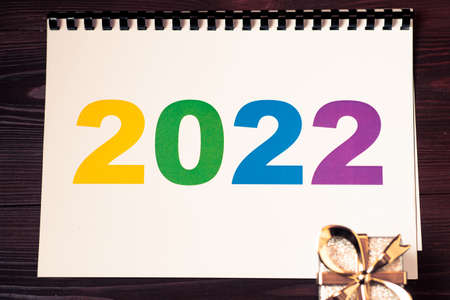 2022 multicolored numbers on a piece of paper and a gift lying.