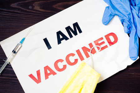 I am vaccinated. Words on a piece of paper with a medical mask with gloves and a syringe.の写真素材