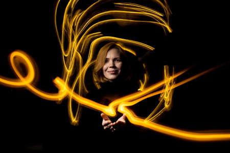 Woman surrounded by drawn light at long exposure. Energy flows concept.