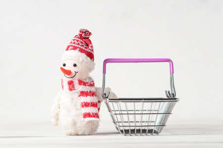 Toy snowman and shopping basket on a white background. Christmas, New Years sales concept.の写真素材