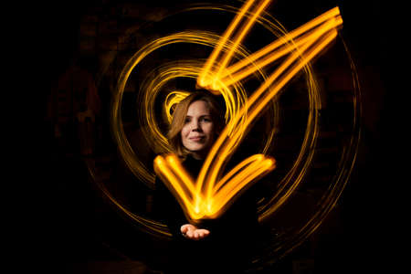 Woman reaching the goal, energy concept. The sign of a bright lightning drawn by light at a long exposure on a woman's hand.の写真素材