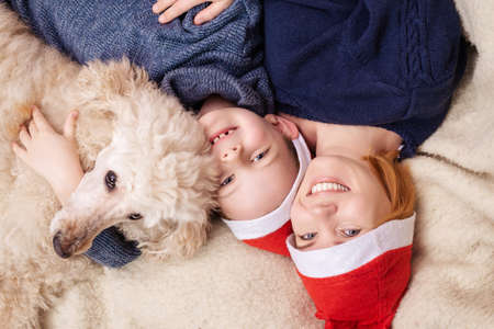 A woman with a young boy son and a dog dressed in New Year's hats is lying on the couch and smiling. View from above.の写真素材