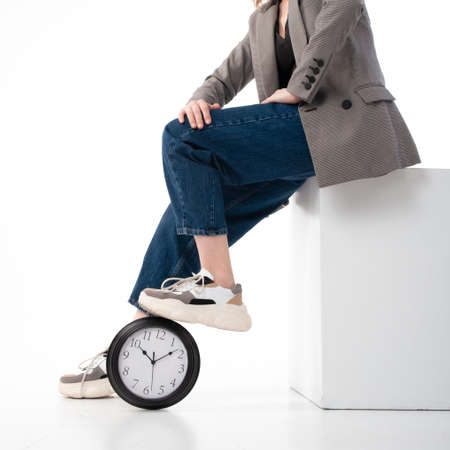 Deadline concept, time management. The woman stepped on the big clock. On white background.の写真素材