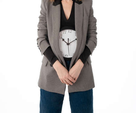 Menstruation time concept. An unrecognizable woman holds a watch in the lower abdomen. Isolated on...
