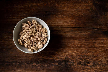 Walnuts in a plate. Dark wooden background. Healthy, wholesome food. Place for your text.の写真素材