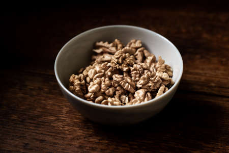Walnuts in a plate. Dark wooden background. Healthy, wholesome food.の写真素材