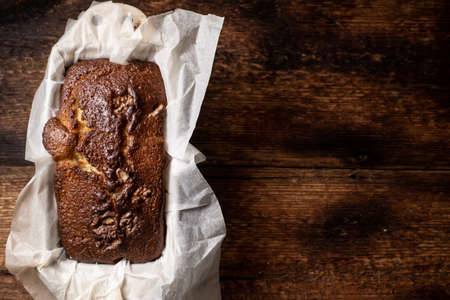 Baked banana bread. Dark wooden background. Bread with walnuts. Place for your text.