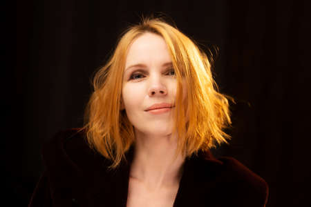 Portrait of an attractive red-haired woman against a dark background. A middle-aged woman, forty...