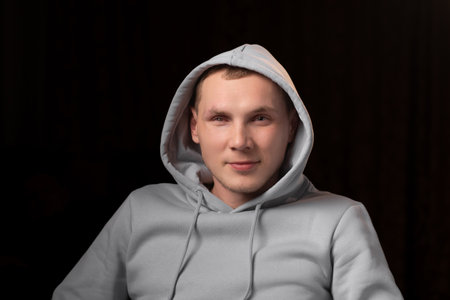 Portrait of a young man with a mutilated eye. dark background. A young man looks into the camera. Eye injury, recovery after surgery.の写真素材