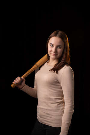 Young woman with a bat on a dark background. Self-defense, psychological protection, mental strength, inner peace concept.の写真素材