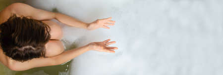 A woman is taking a bubble bath. view from above. Banner, place for text. Relaxation, spa concept.