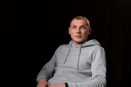 Portrait of a young man with a mutilated eye. dark background. A young man looks into the camera....