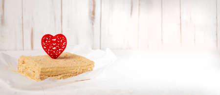 Cake with a red heart. Napoleon cake with Valentine's Day decor. minimalist design. white background. Banner, place for text.の写真素材