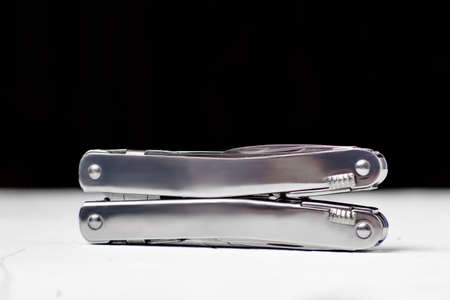Steel multifunctional folding knife on a white and black background.