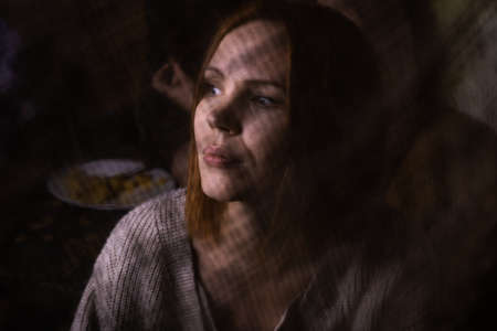 Anonymous, hidden image of a woman. A woman in the dark behind a cloth. Rethinking life, meditations, depressive psychological states concept.の写真素材