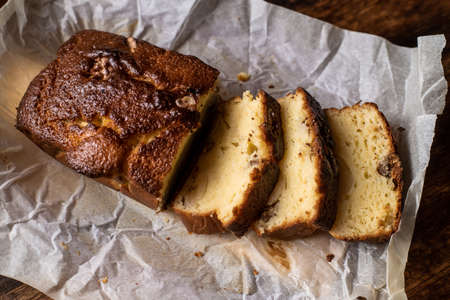 Baked banana bread. Cut into pieces. Dark wooden background. Bread with walnuts.の写真素材
