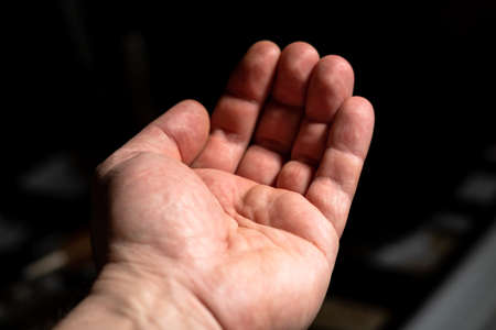 Empty male hand. Outstretched hand of a man on a dark background.の写真素材