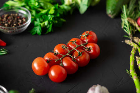 Branch of cherry tomatoes. dark background. Various vegetables. Vegetarian food. Raw food diet.