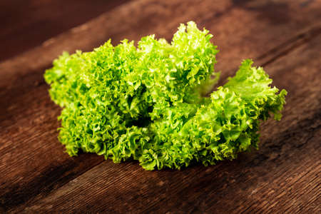 Green lettuce salad on a wooden background. Vegetarianism concept, plant food.