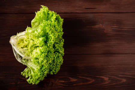 Green lettuce salad on a wooden background. Vegetarianism concept, plant food. Place for text.の写真素材