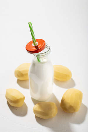 Potato milk concept. Bottle with potato milk on a white background. An alternative to animal products. Vegan food.の写真素材