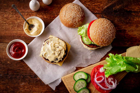 Ingredients for hamburger, cheeseburger. wooden background. The hamburger is smeared with sauce. Cooking. Hamburger day.の写真素材