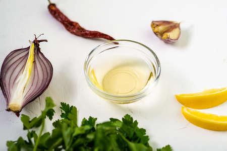 Sauce preparation. Lemon, olive oil, parsley, cilantro, garlic on a white background.の写真素材