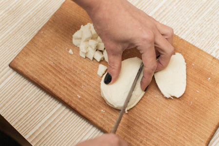 Woman slices cheese on a cutting board.の写真素材