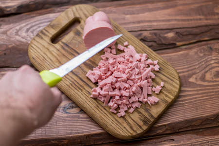 Chopped boiled sausage on a wooden board.の写真素材