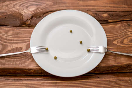 diet concept. Several peas lying on a white plate. Restriction in nutrition.の写真素材
