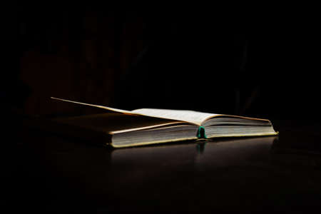 An open book on the table. Black background. Learning, reading concept.の写真素材