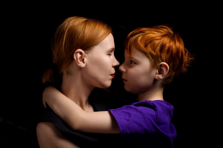 Mom and young son are hugging. Black background. Love between mother and son. mother's day. family relationships.の写真素材