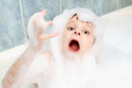 A boy in soapy suds is washing in a bath. Hygiene, cleanliness concept.