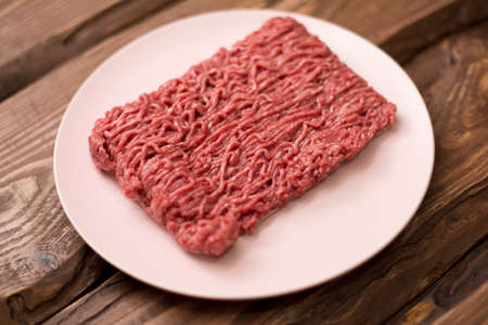 Fresh minced meat on a plate on a wooden background for cooking.の写真素材