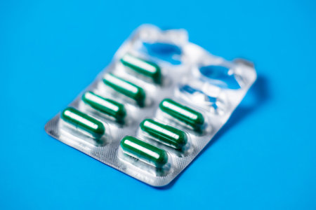 Started packing of tablets with green capsules. Blue background background. Probiotics, vitamins concept.の写真素材