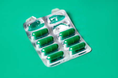 Started packing of tablets with green capsules. green background. Probiotics, vitamins concept.の写真素材