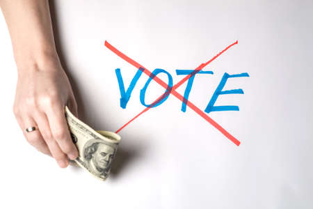 Buying votes of voters concept. A woman's hand holds one hundred US dollars against the background...